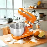 Batidora planetaria Finezza FZ-6812B de color naranja con tazón de acero inoxidable y tres accesorios de batido sobre un fondo blanco.