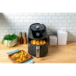 Freidora de aire Oster manual de 4 litros negra Diamond Force CKSTAF40MDF-053 con perillas de control de tiempo y temperatura sobre una encimera de cocina.