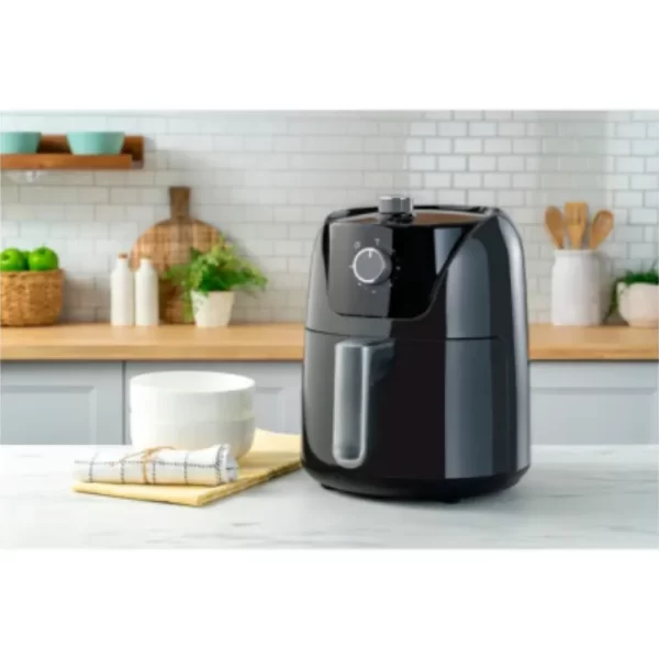 Freidora de aire Oster manual de 4 litros negra Diamond Force CKSTAF40MDF-053 con perillas de control de tiempo y temperatura sobre una encimera de cocina.